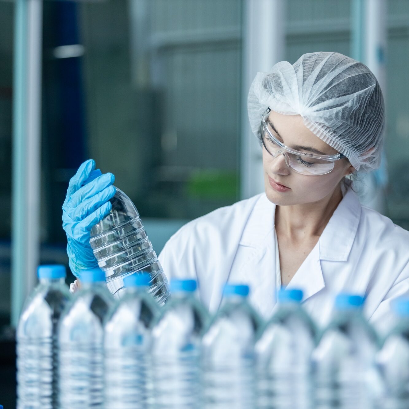 woman factory worker holding plastic bottle line manufacture drink water.